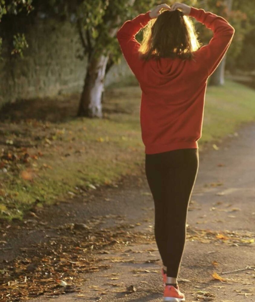 Woman walking in nature with hands on her head