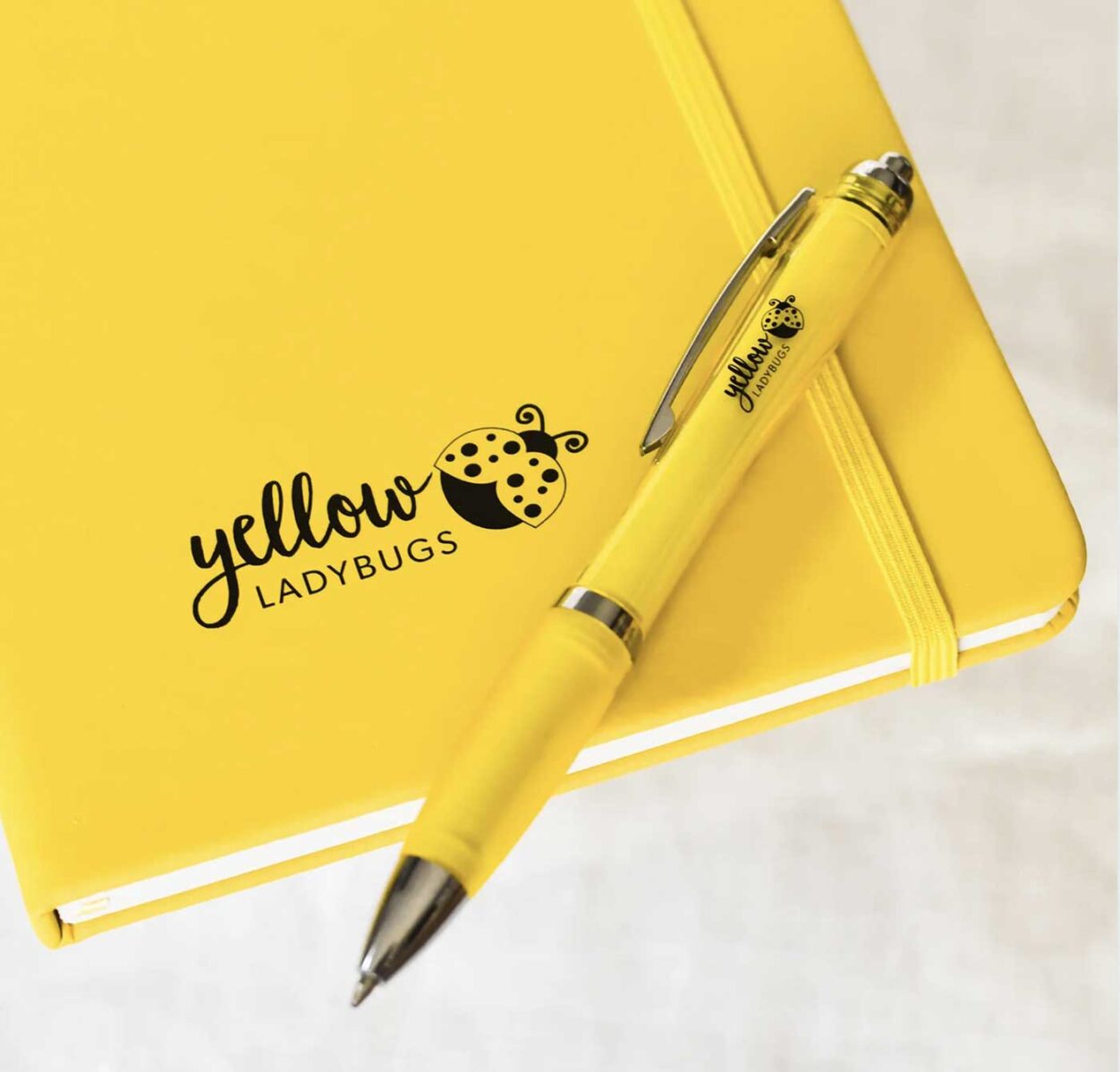 Yellow ladybugs logo on notepad and pen